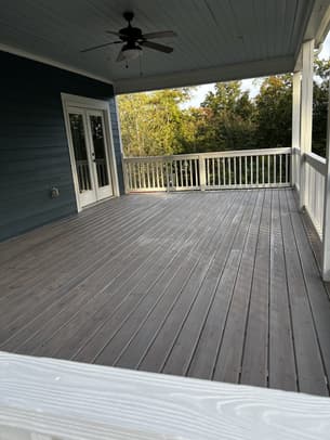 Newly stained wooden deck stairs with black metal railings and a warm honey finish.