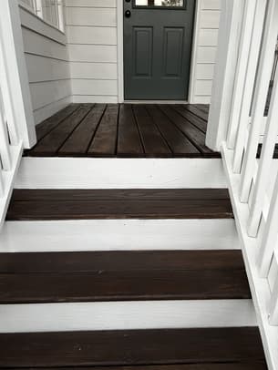 Newly stained wooden deck stairs with black metal railings and a warm honey finish.